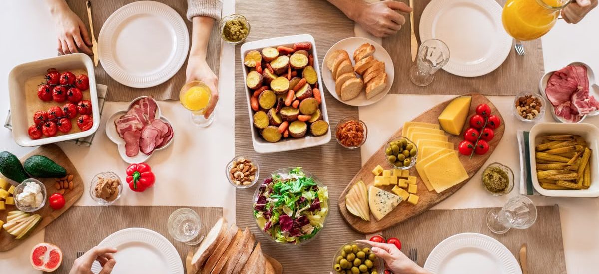 A top view of a diverse spread of food and drinks set for a family lunch.